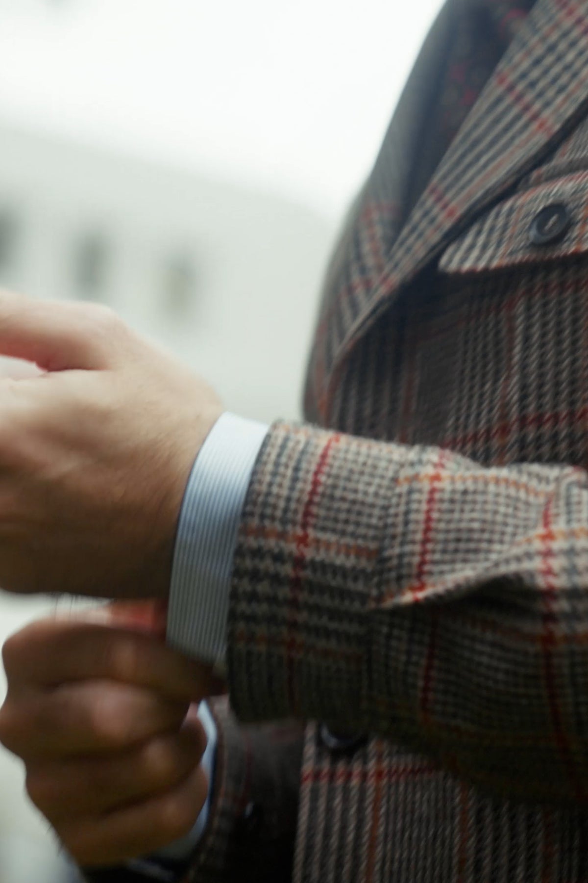 Shirt cuff under a Prince of Wales check safari jacket