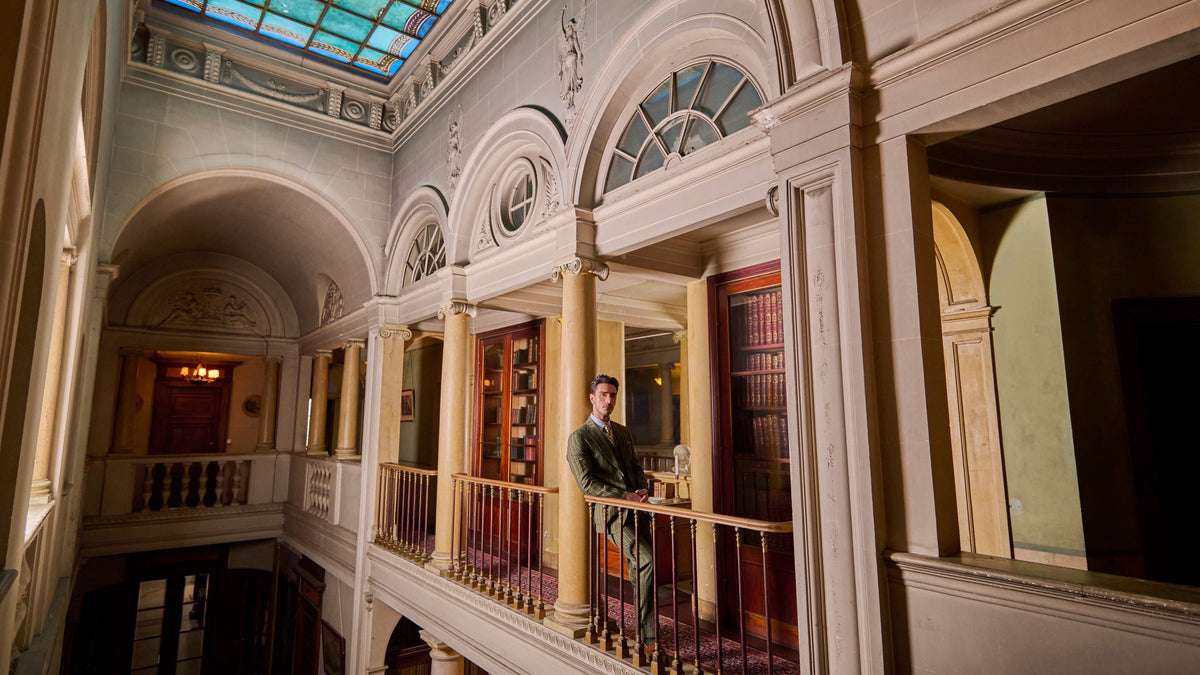 Green striped suit in the library of a château, beneath a glass roof