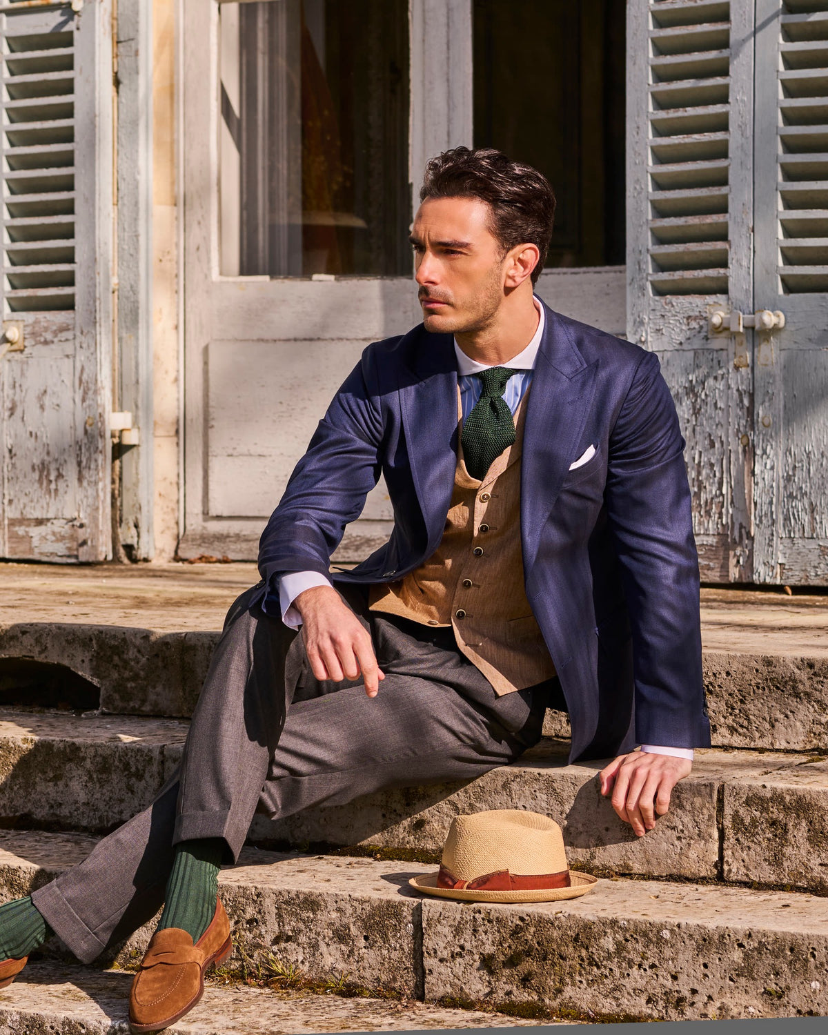 Rome jacket in blue herringbone, seated on the front steps of a château