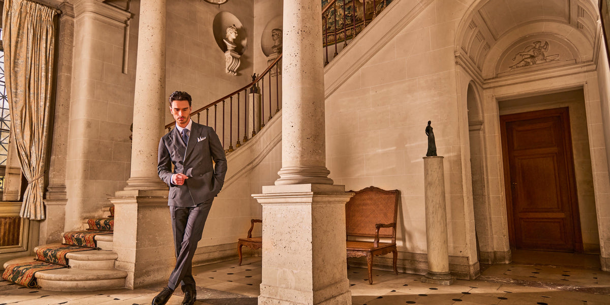 Grey double-breasted suit in the stone entrance hall of a château